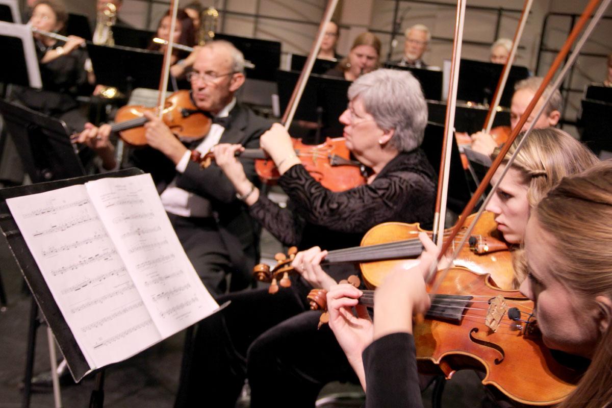 Multiple students playing violins with sheet music on stand